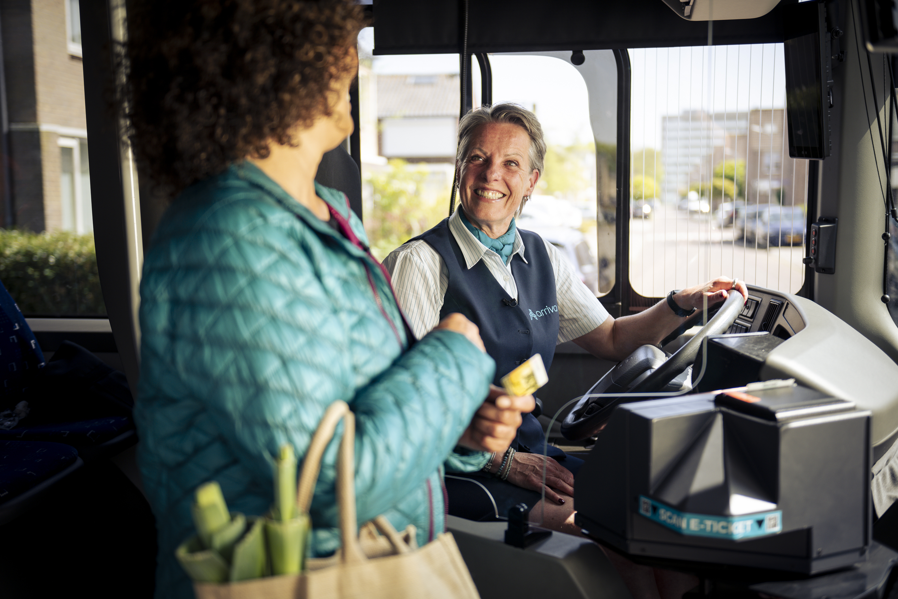 Een vriendelijke Arriva-chauffeur helpt een passagier bij het instappen en betalen in de bus.
