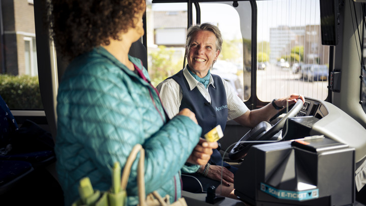 Mevrouw checkt in met haar ov pas Een vriendelijke Arriva-chauffeur helpt een passagier bij het instappen en betalen in de bus.